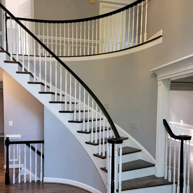 Curved staircase with dark stained treads and white balusters