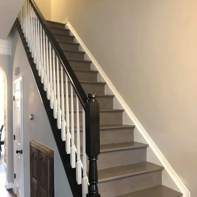 Staircase with grey luxury vinyl plank treads and a black newel post