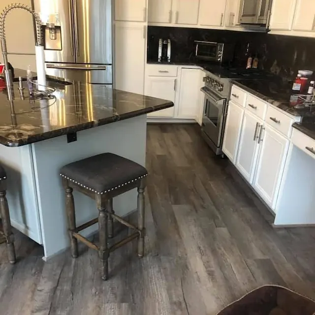 Kitchen with a grey luxury vinyl plank floor and a granite island