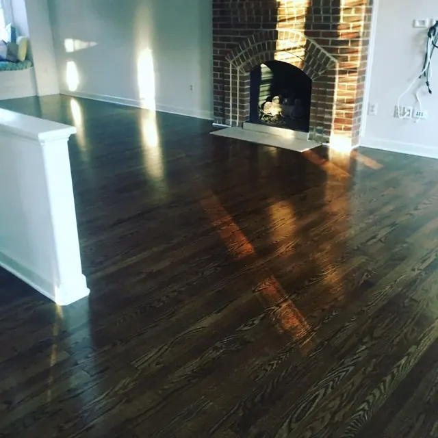 Dark refinished oak floor with a gloss finish beside a brick fireplace