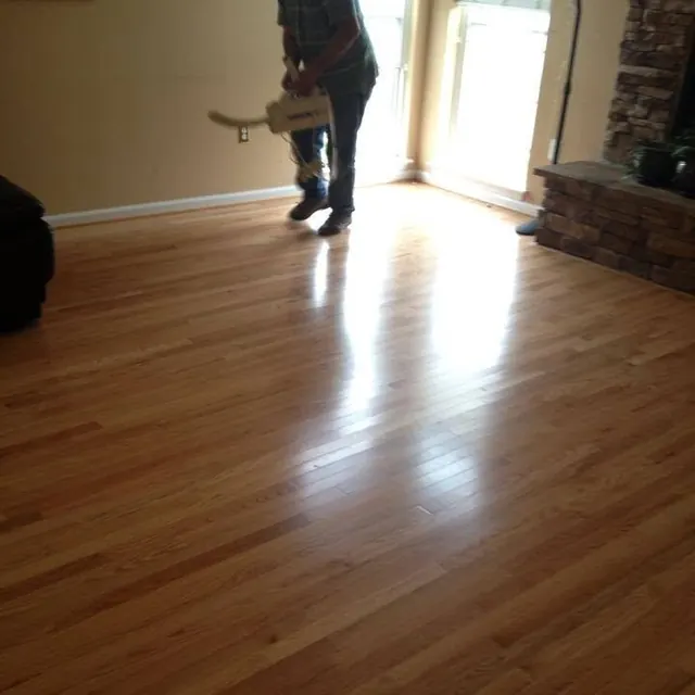 AG Construction crew member running a floor buffer over a red oak floor