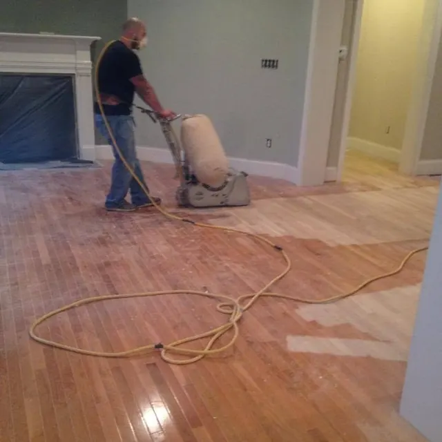 AG Construction crew member sanding a floor with a drum sander